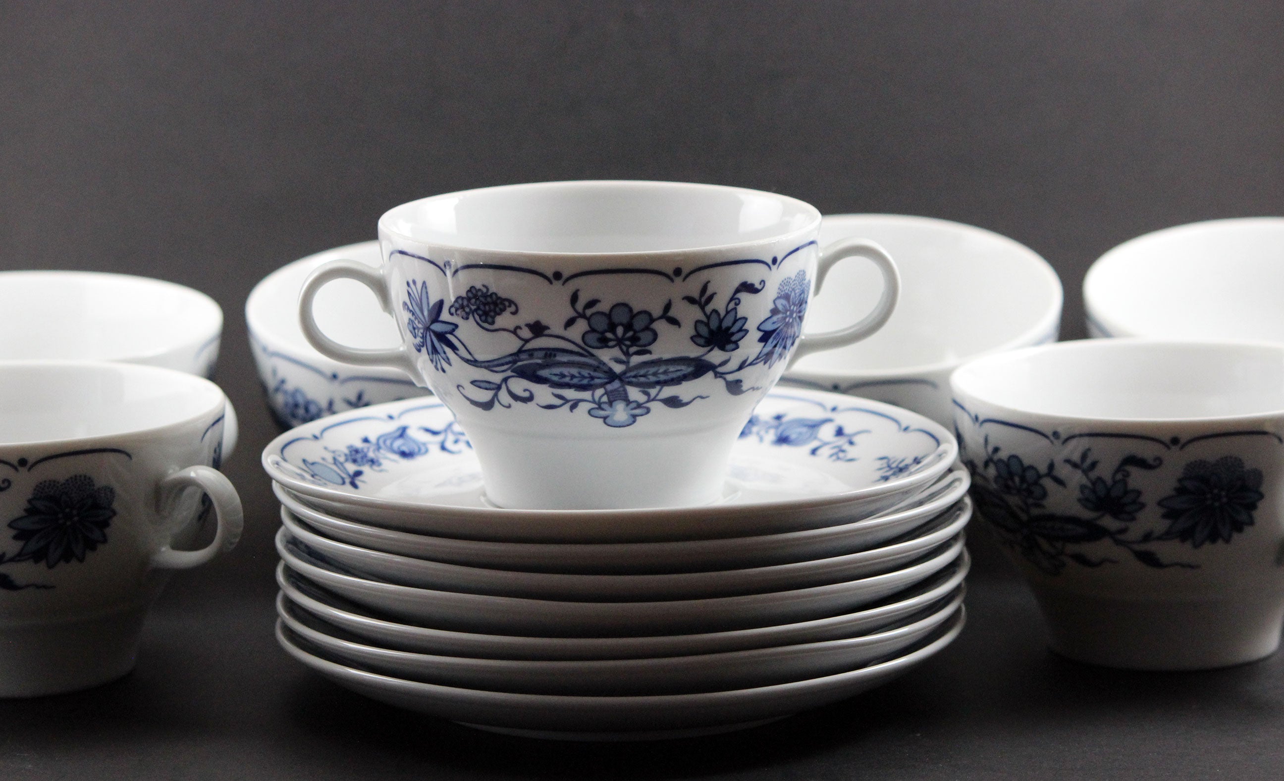 Set of white porcelain soup bowls with blue floral patterns on a gray background