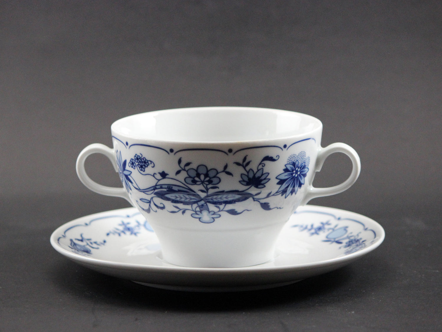 Set of white porcelain soup bowls with blue floral patterns on a gray background