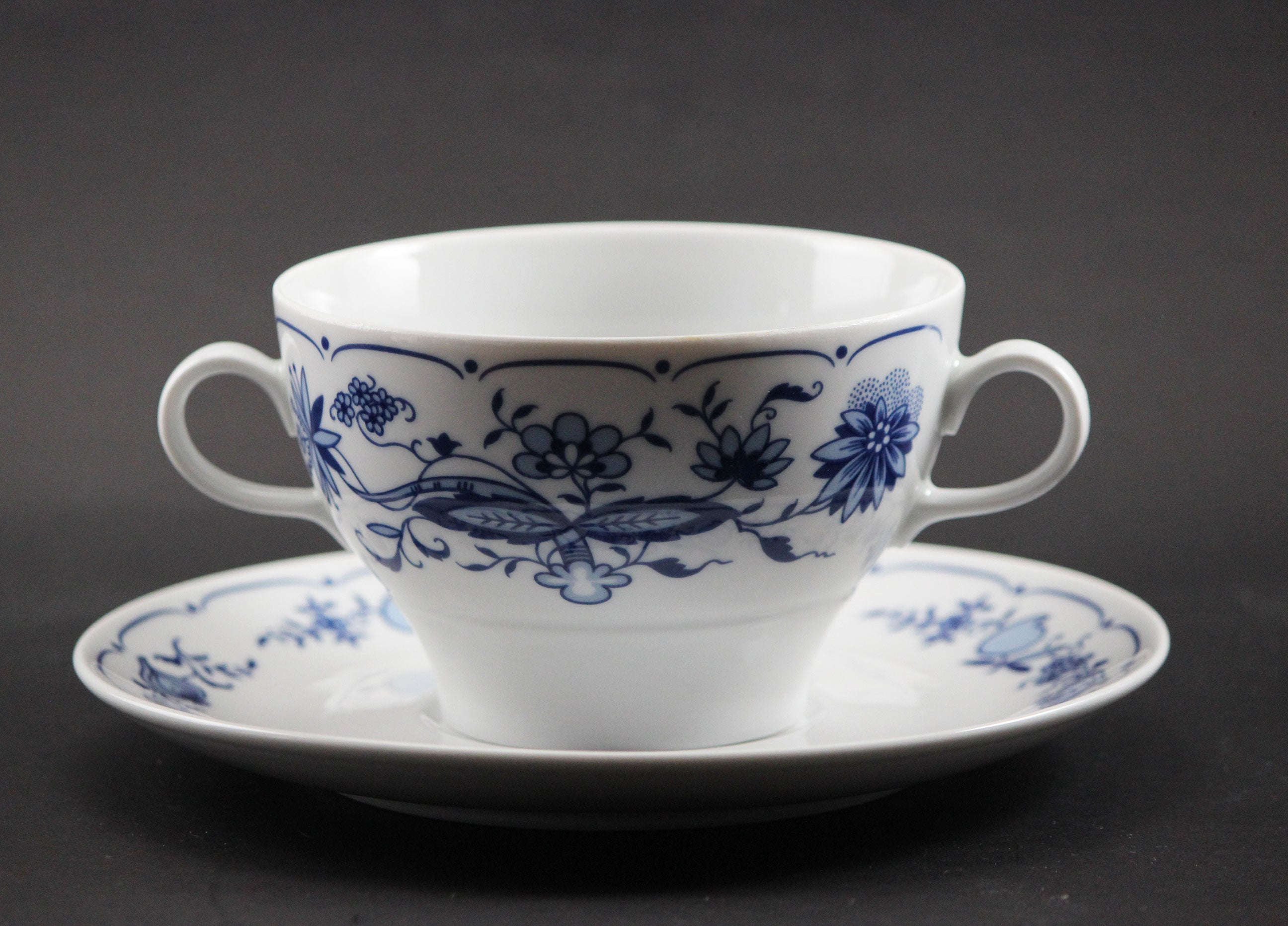 Set of white porcelain soup bowls with blue floral patterns on a gray background