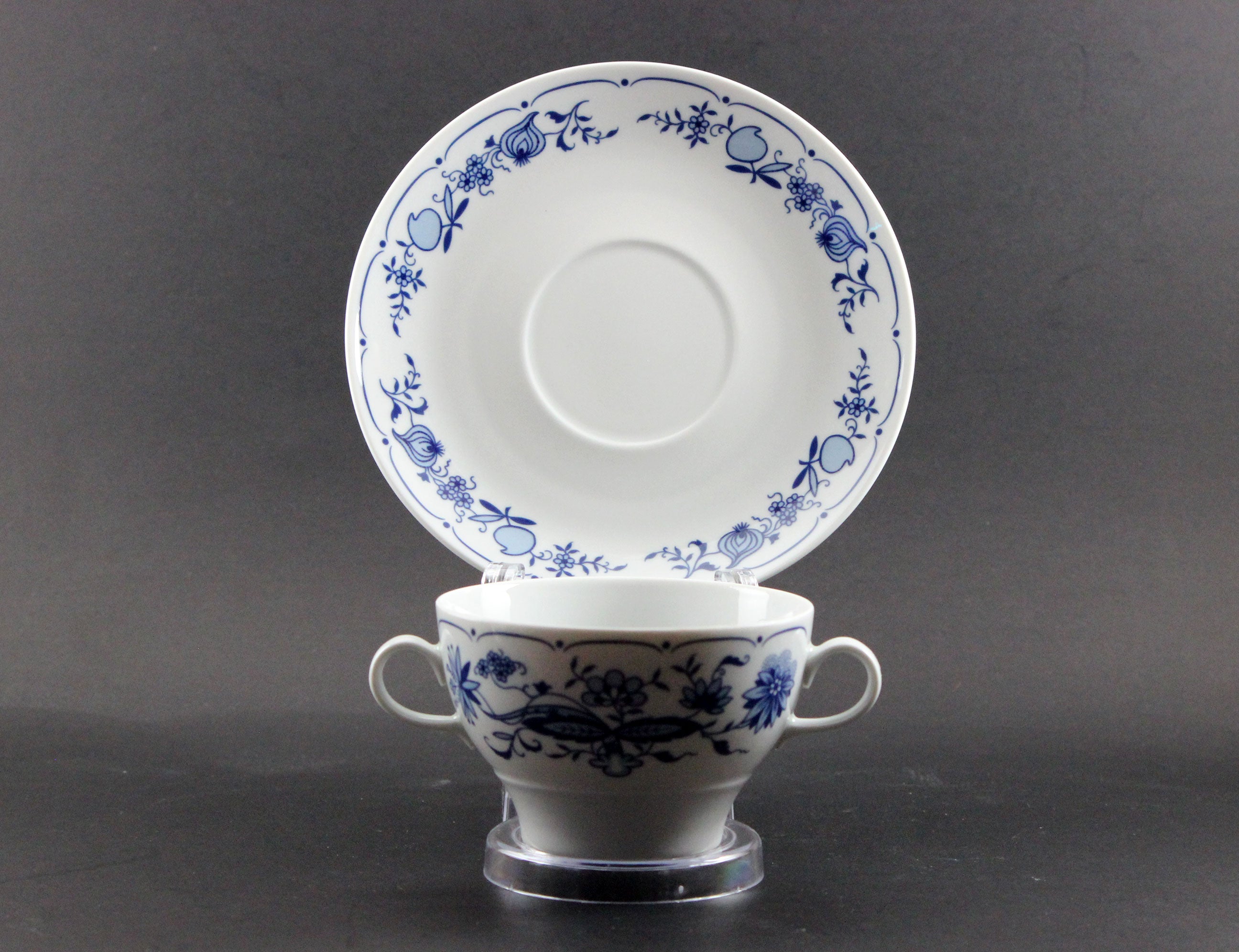 Set of white porcelain soup bowls with blue floral patterns on a gray background