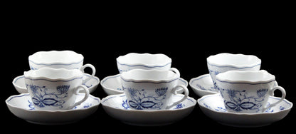 Set of ceramic teacups and saucers with blue floral patterns on a dark background