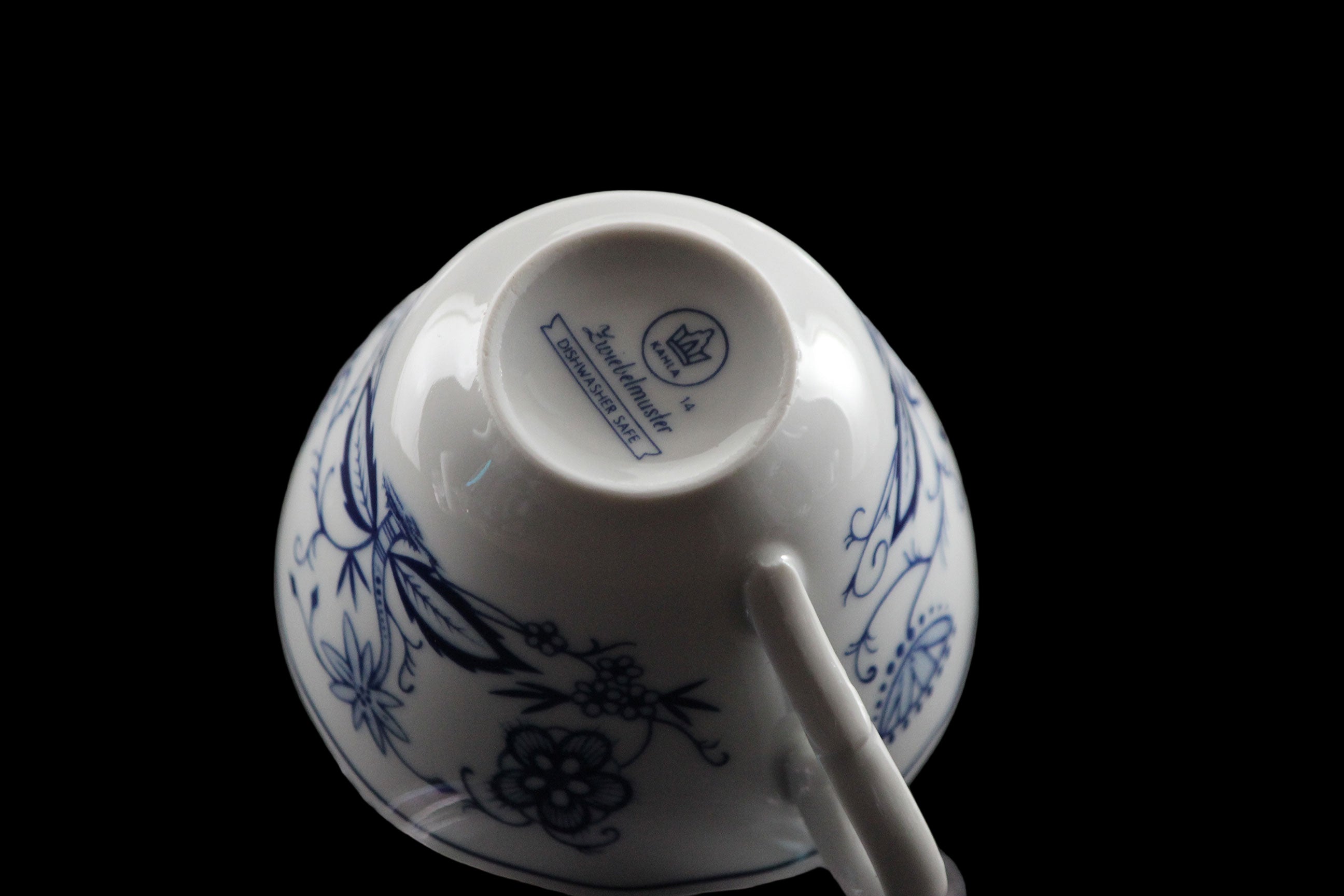 Porcelain teacup and saucer with blue floral patterns on a dark background