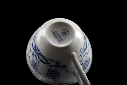 Porcelain teacup and saucer with blue floral patterns on a dark background
