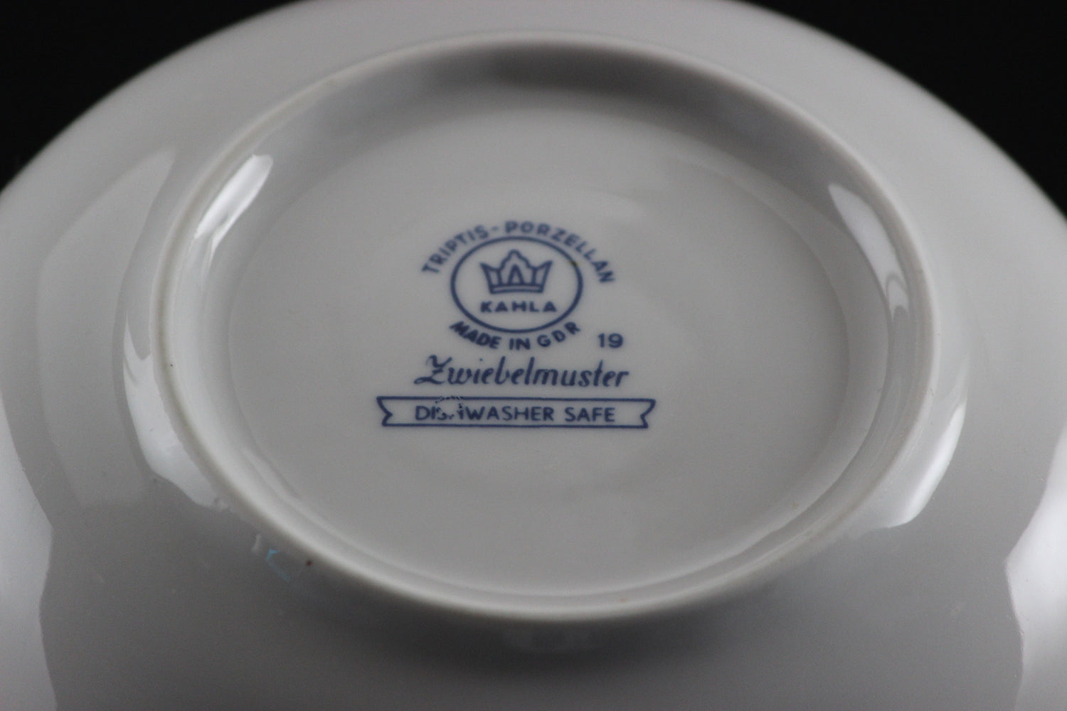Porcelain teacup and saucer with blue floral patterns on a dark background