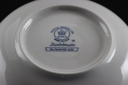 Porcelain teacup and saucer with blue floral patterns on a dark background