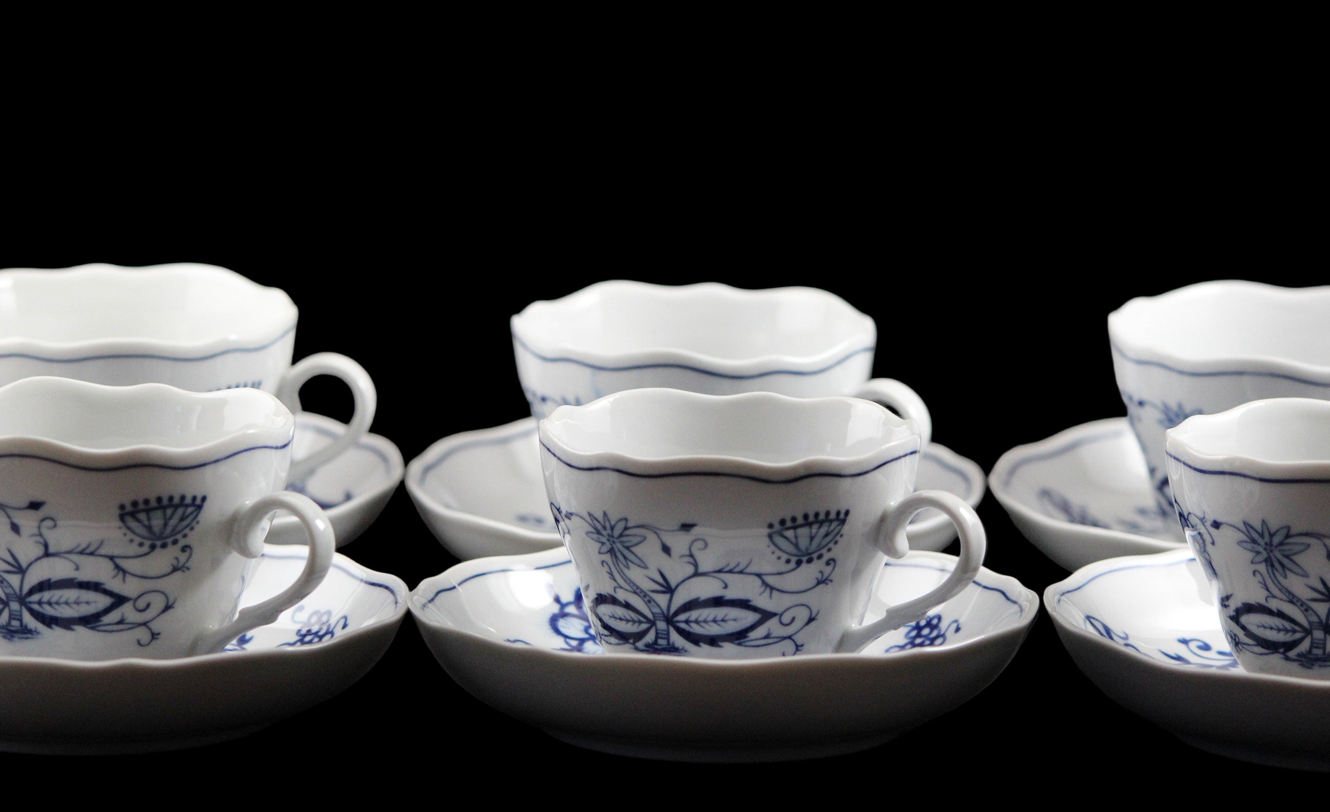 Set of white teacups with blue floral patterns on a dark background