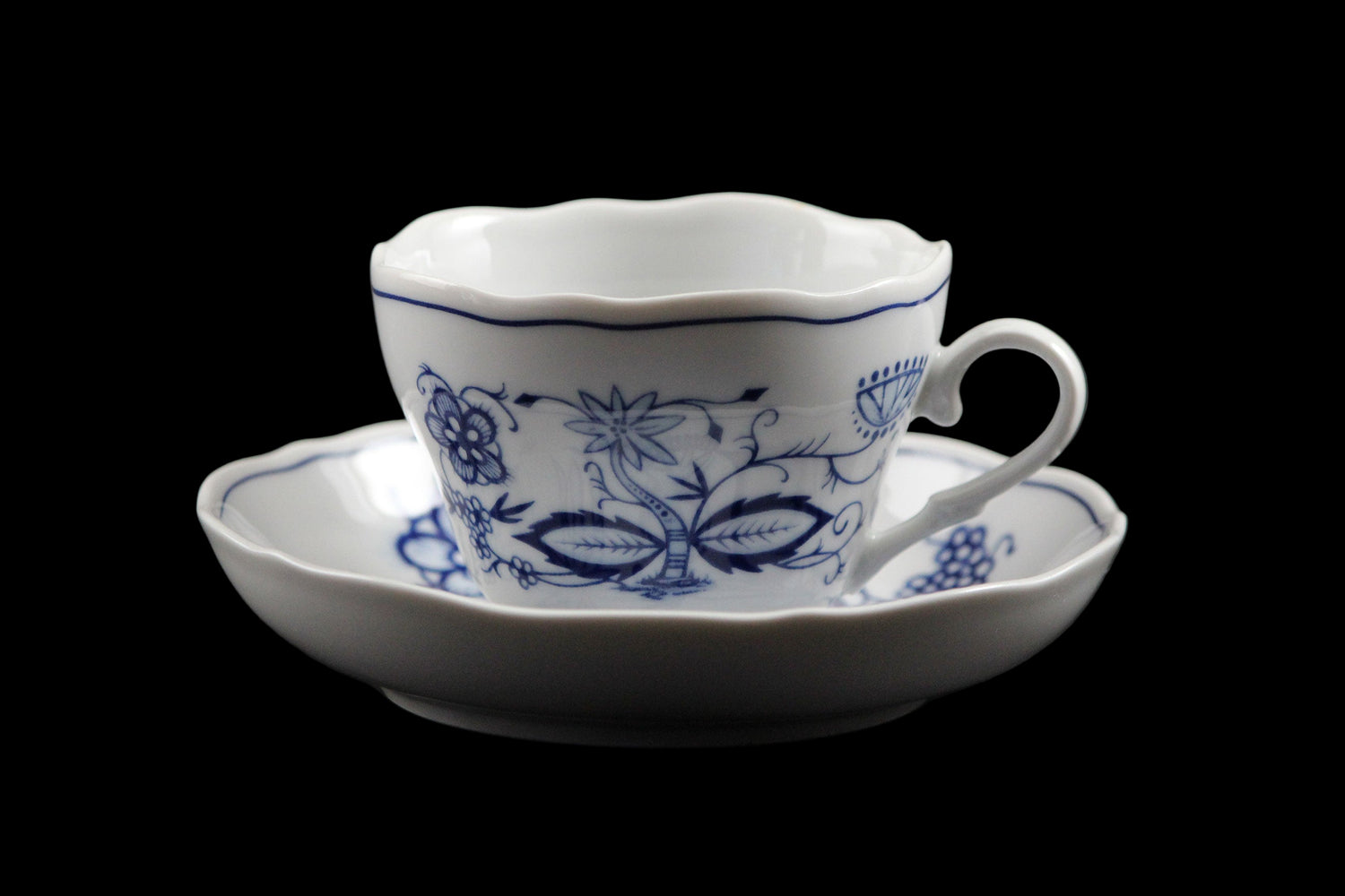 White ceramic cup and saucer with blue floral patterns on a dark background