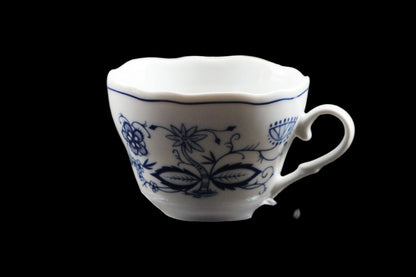 White ceramic cup with blue floral patterns on a clear stand against a dark background
