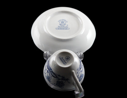 Porcelain teacup and saucer with blue floral patterns on a black background