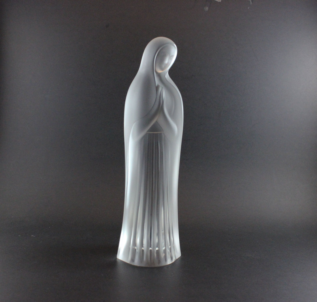 Clear glass statue of a standing figure on a dark background