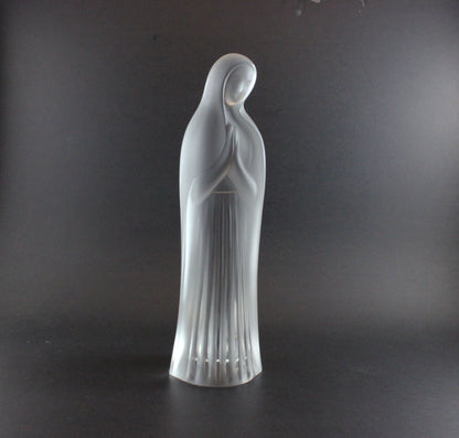 Clear glass statue of a standing figure on a dark background