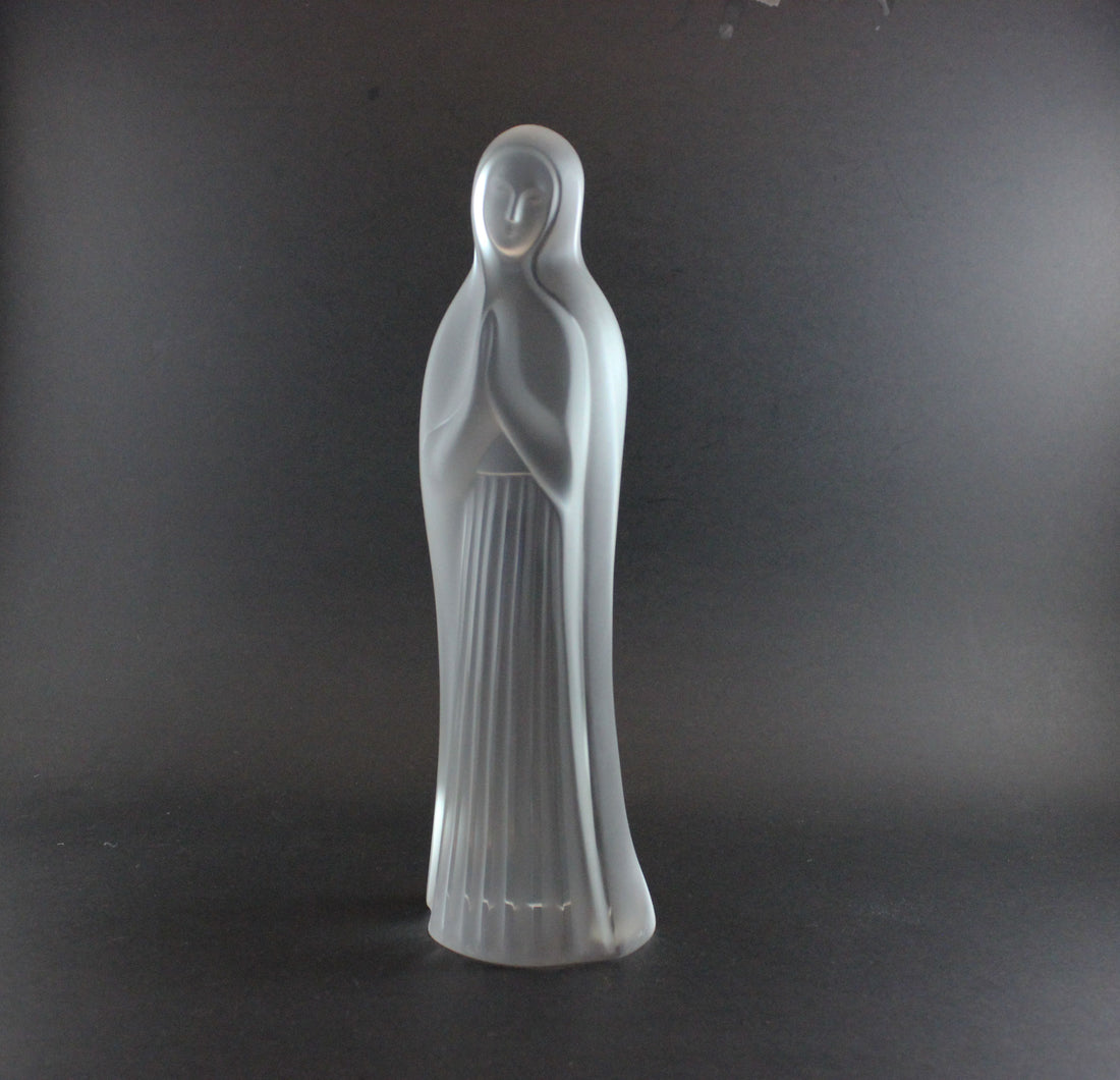 Clear glass statue of a standing figure on a dark background