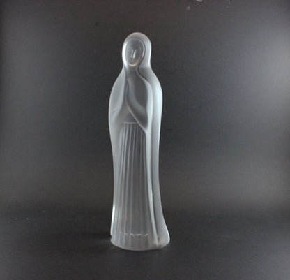 Clear glass statue of a standing figure on a dark background