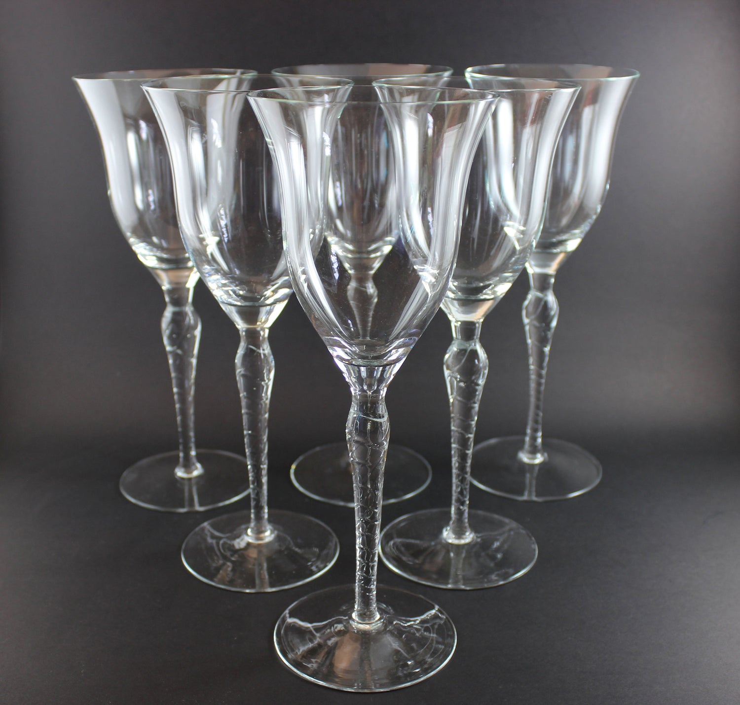 Set of six clear wine glasses on a dark background