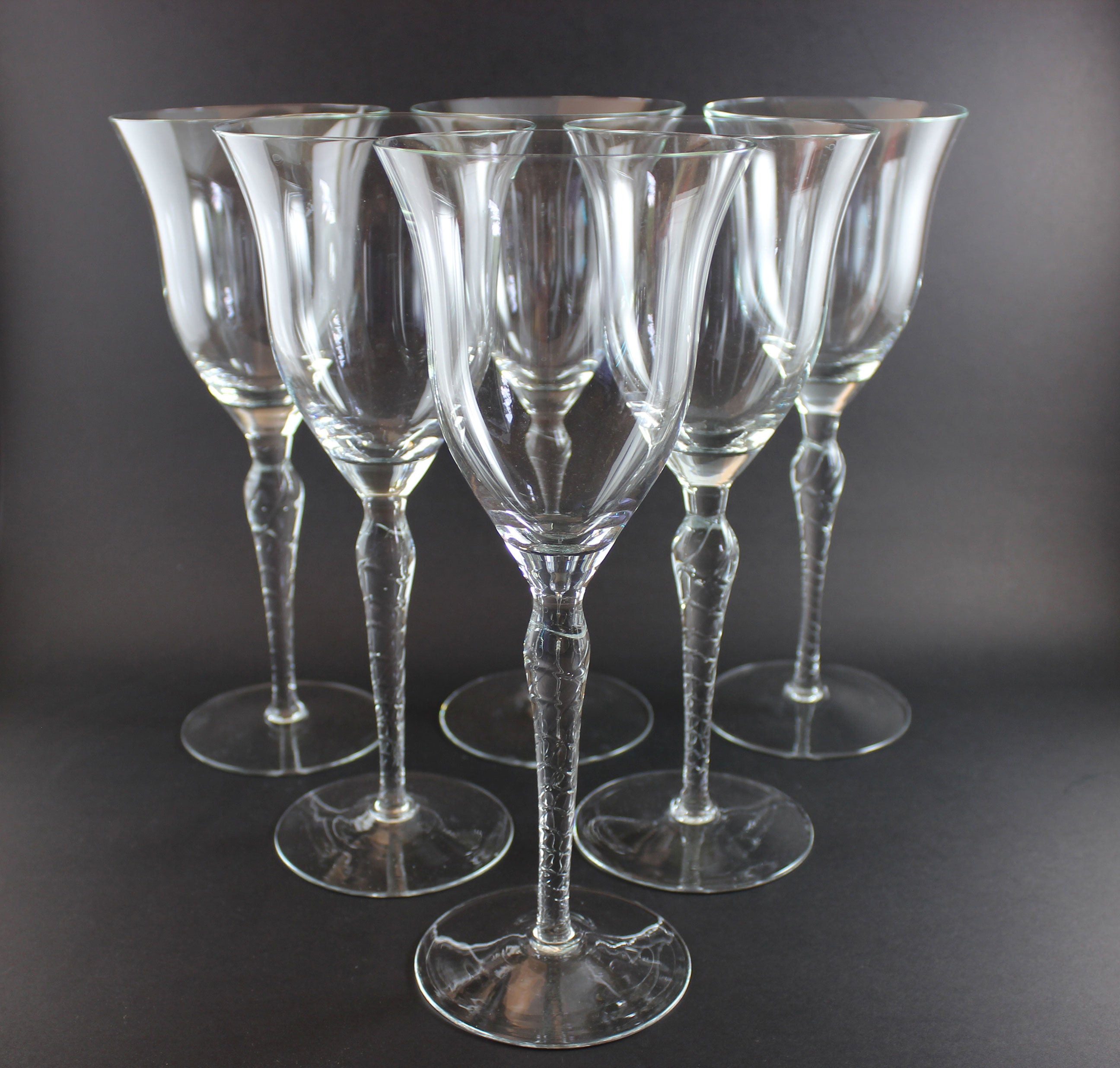 Set of six clear wine glasses on a dark background
