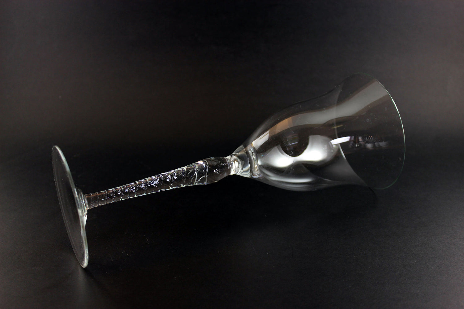 Clear glass wine glass with a long stem on a black background
