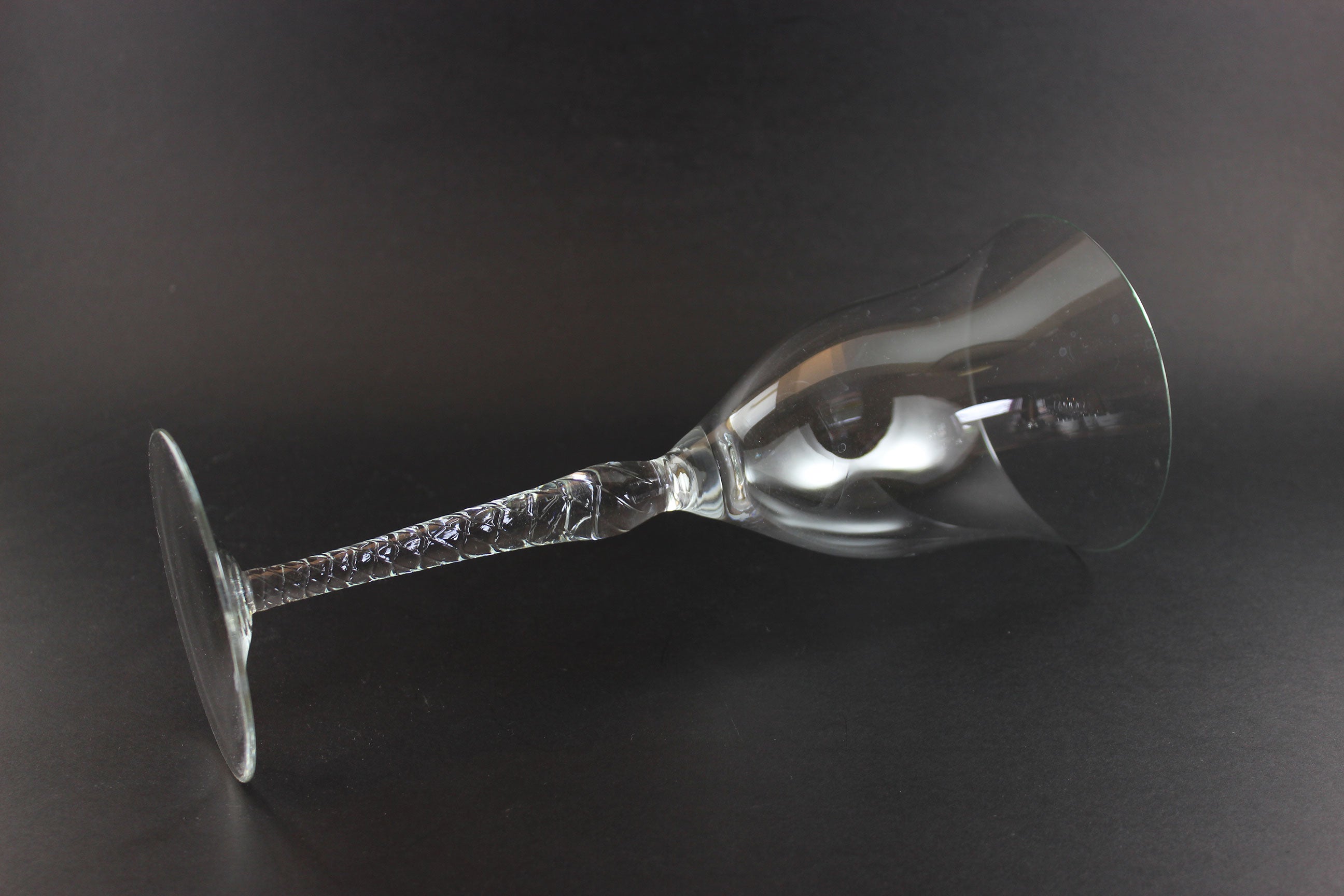 Clear glass wine glass with intricate design on a dark background