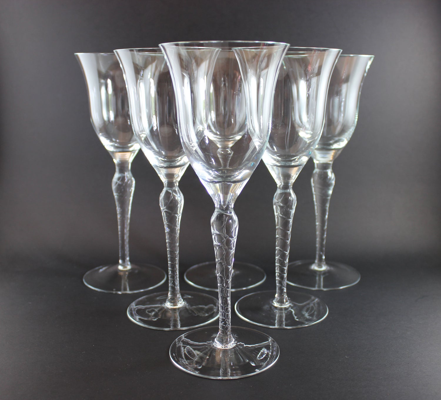 Set of six clear glass wine glasses on a dark background