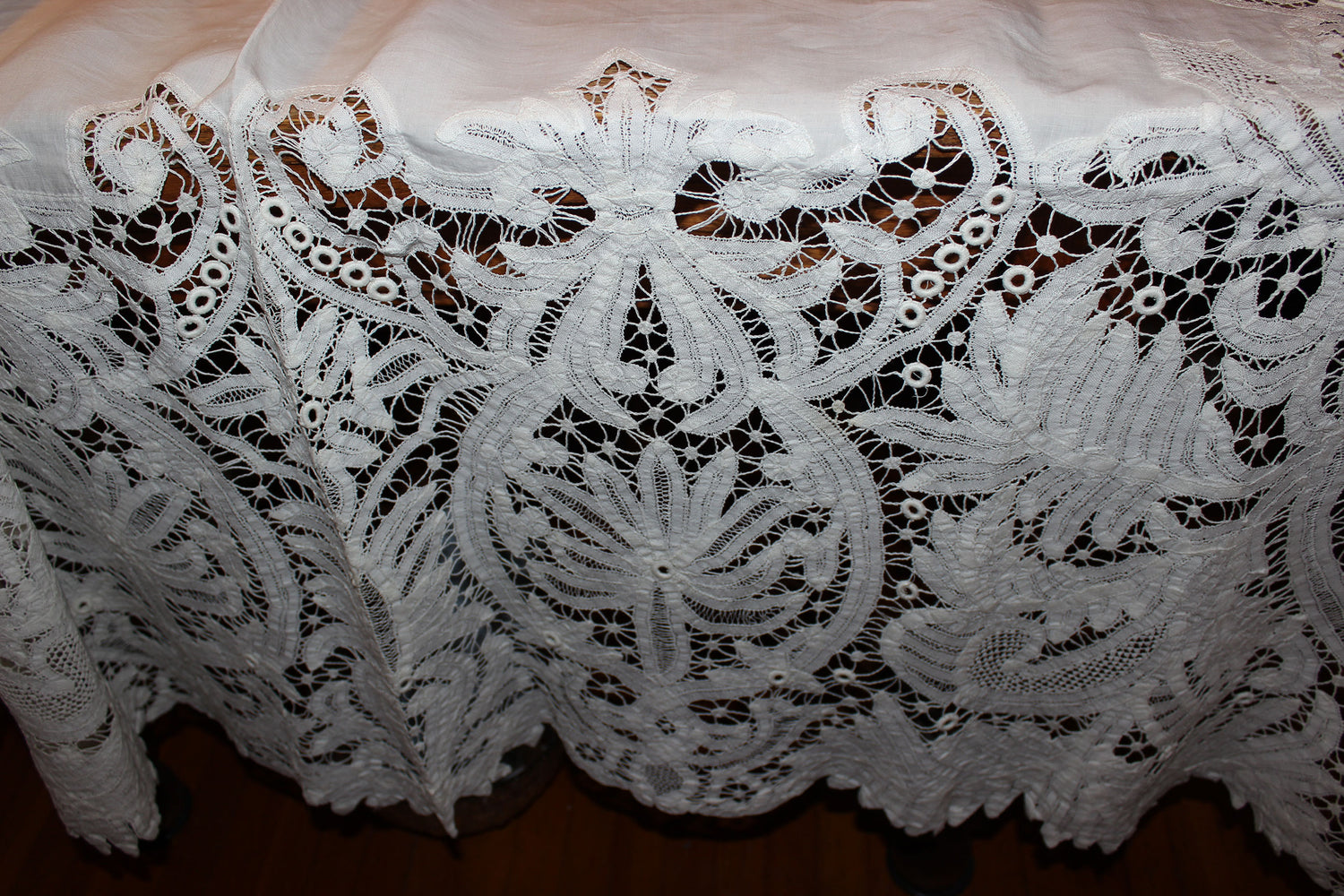 Close-up of intricate white lace fabric on a wooden surface