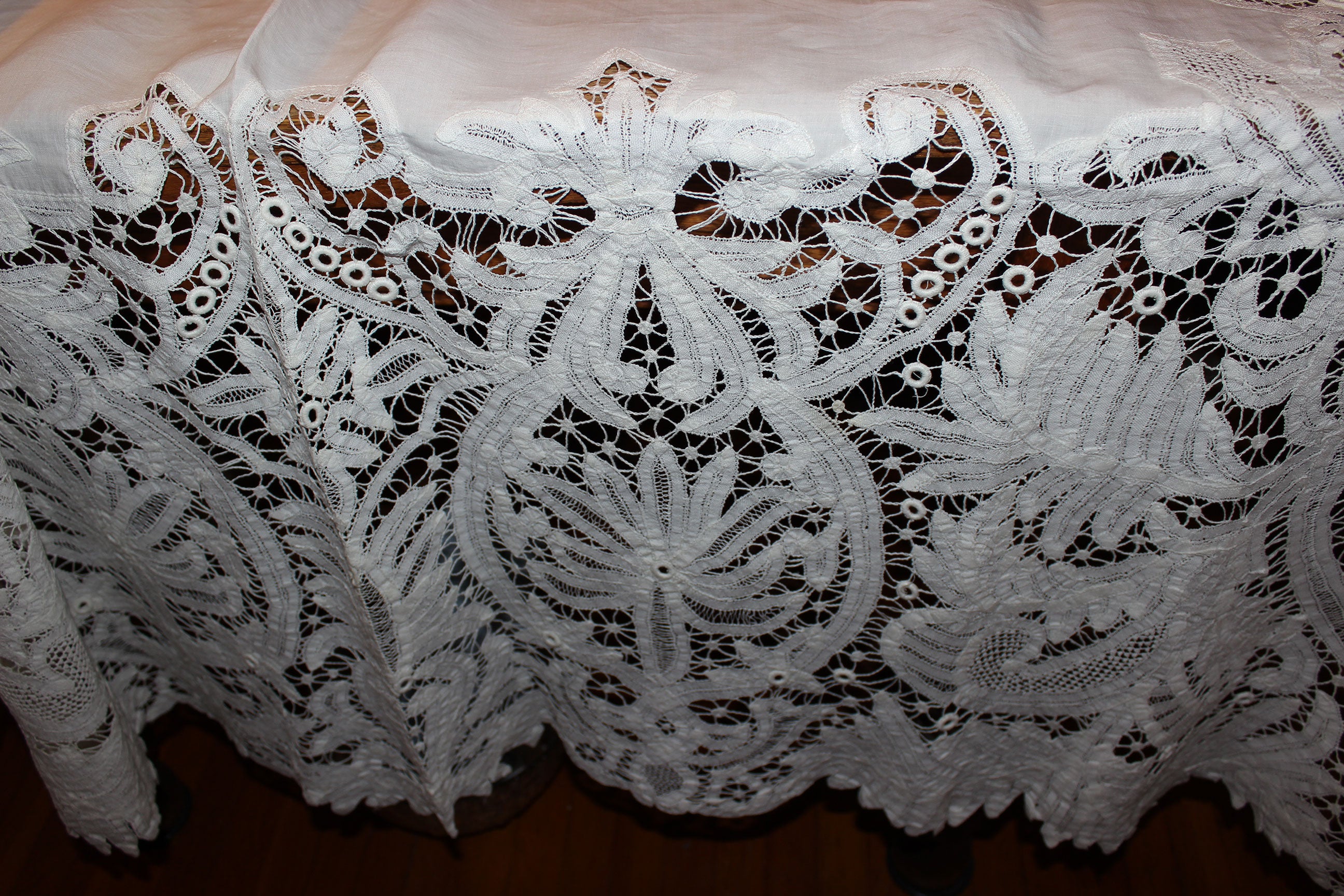 Close-up of intricate white lace fabric on a wooden surface