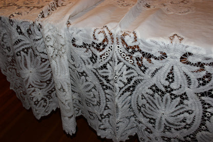 Close-up of a lace tablecloth with intricate patterns on a wooden surface.