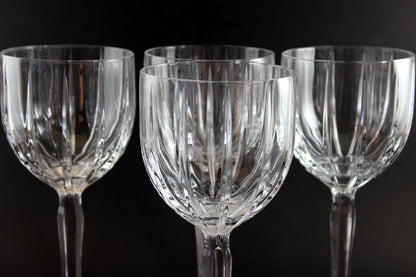 Set of four clear glass wine glasses on a black background