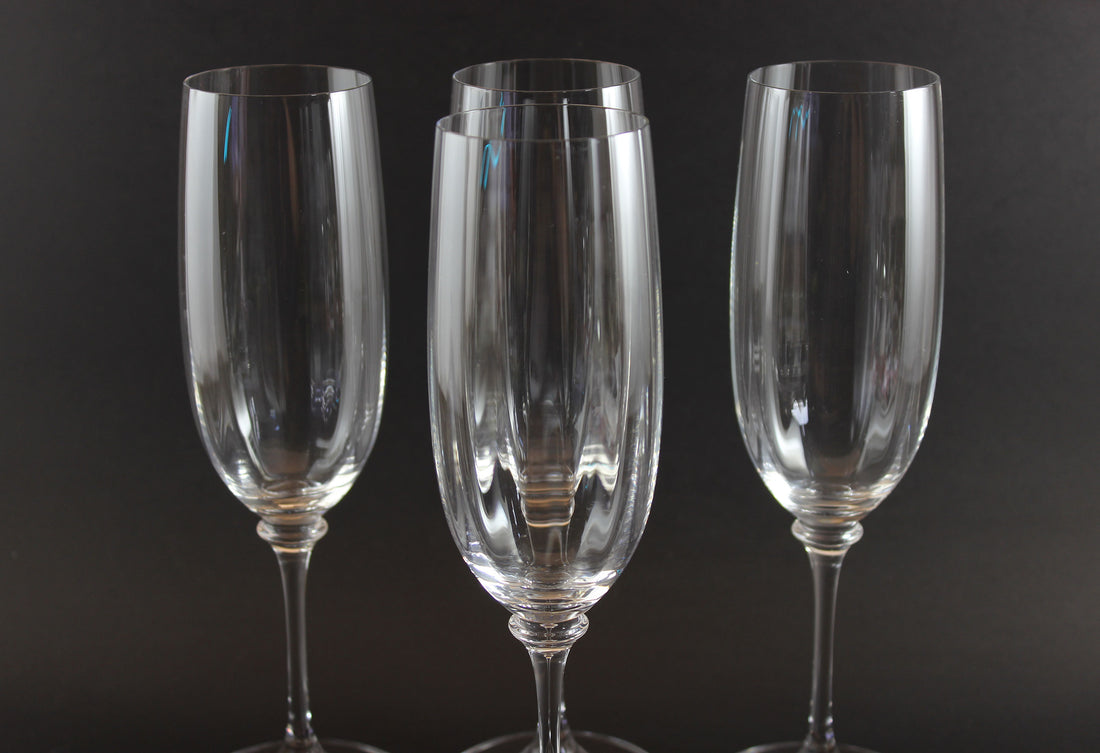 Four Mikasa Stephanie Pattern clear champagne flutes on a black background