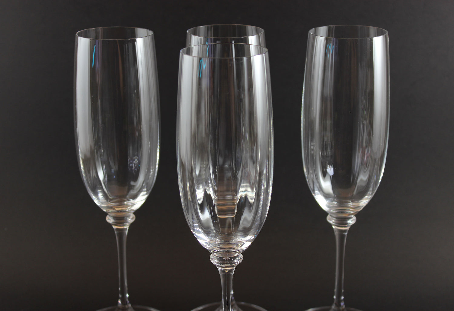 Four Mikasa Stephanie Pattern clear champagne flutes on a black background