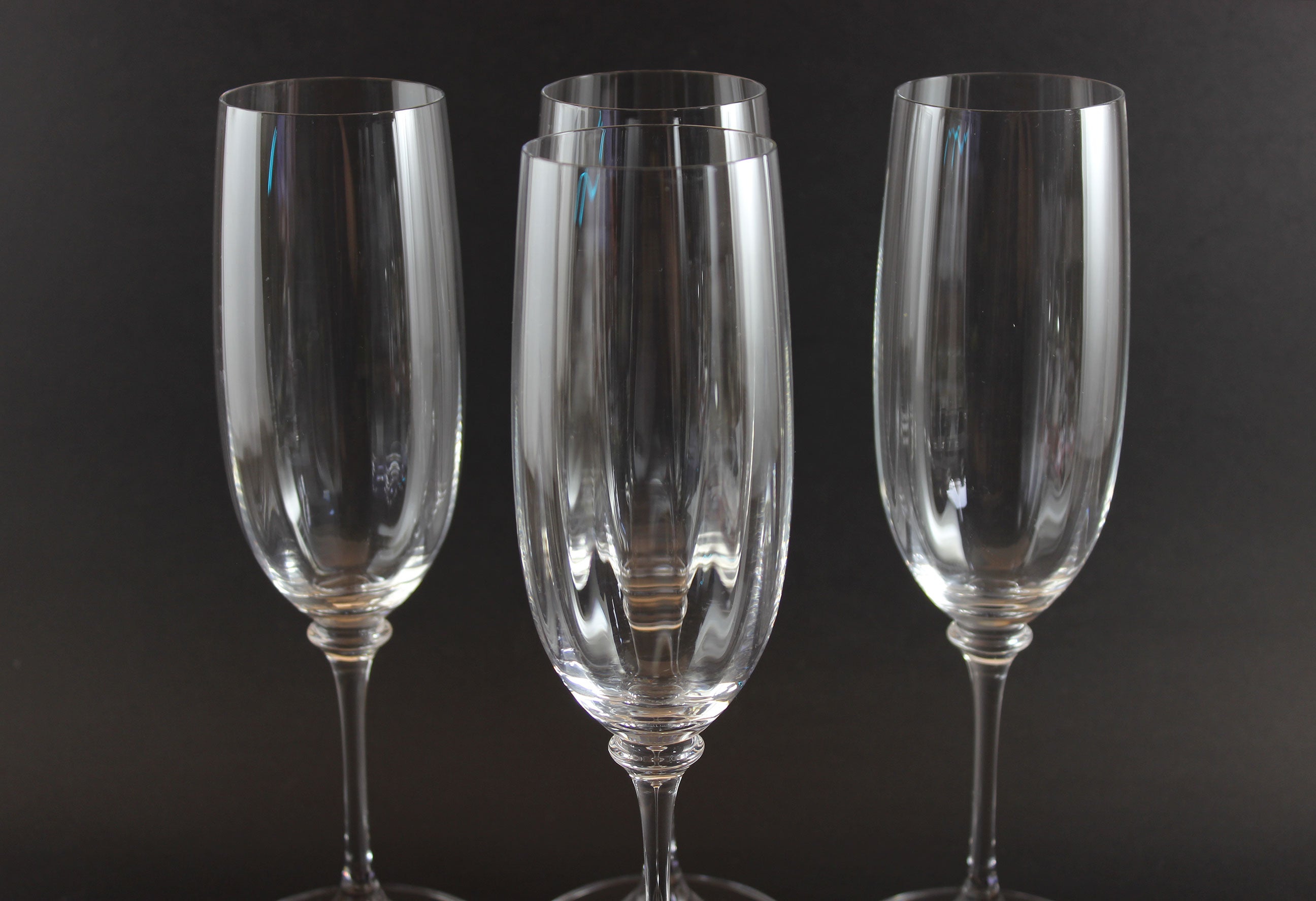 Four Mikasa Stephanie Pattern clear champagne flutes on a black background
