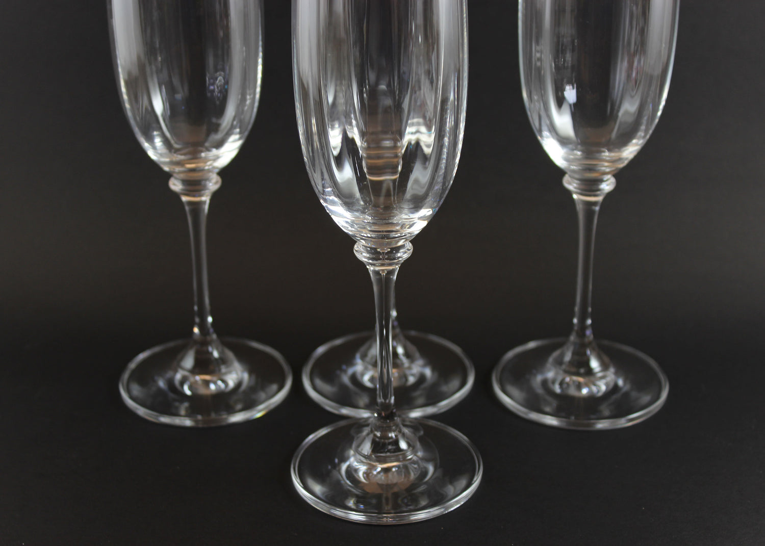 Four Mikasa Stephanie Pattern clear champagne flutes on a black background