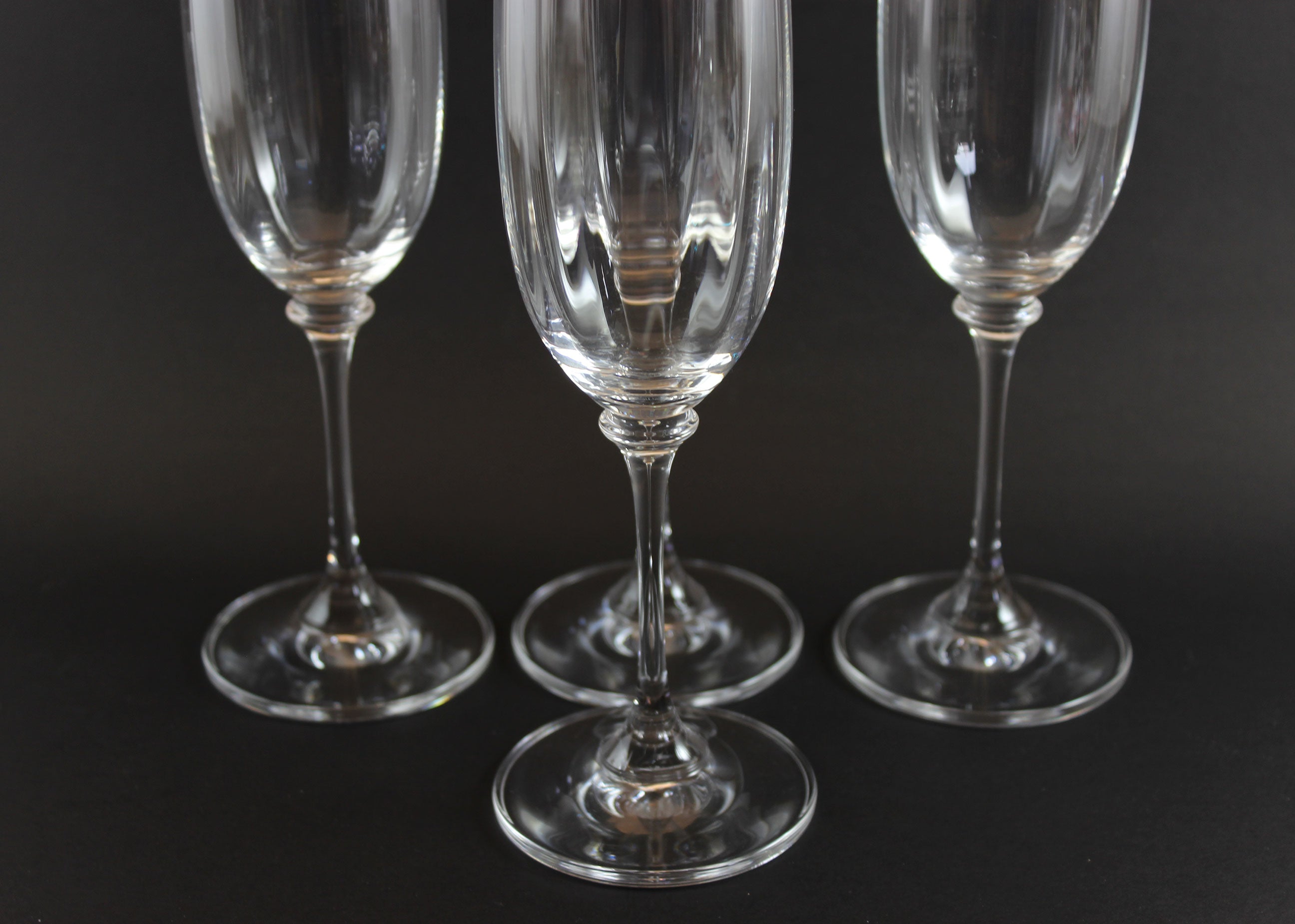 Four Mikasa Stephanie Pattern clear champagne flutes on a black background
