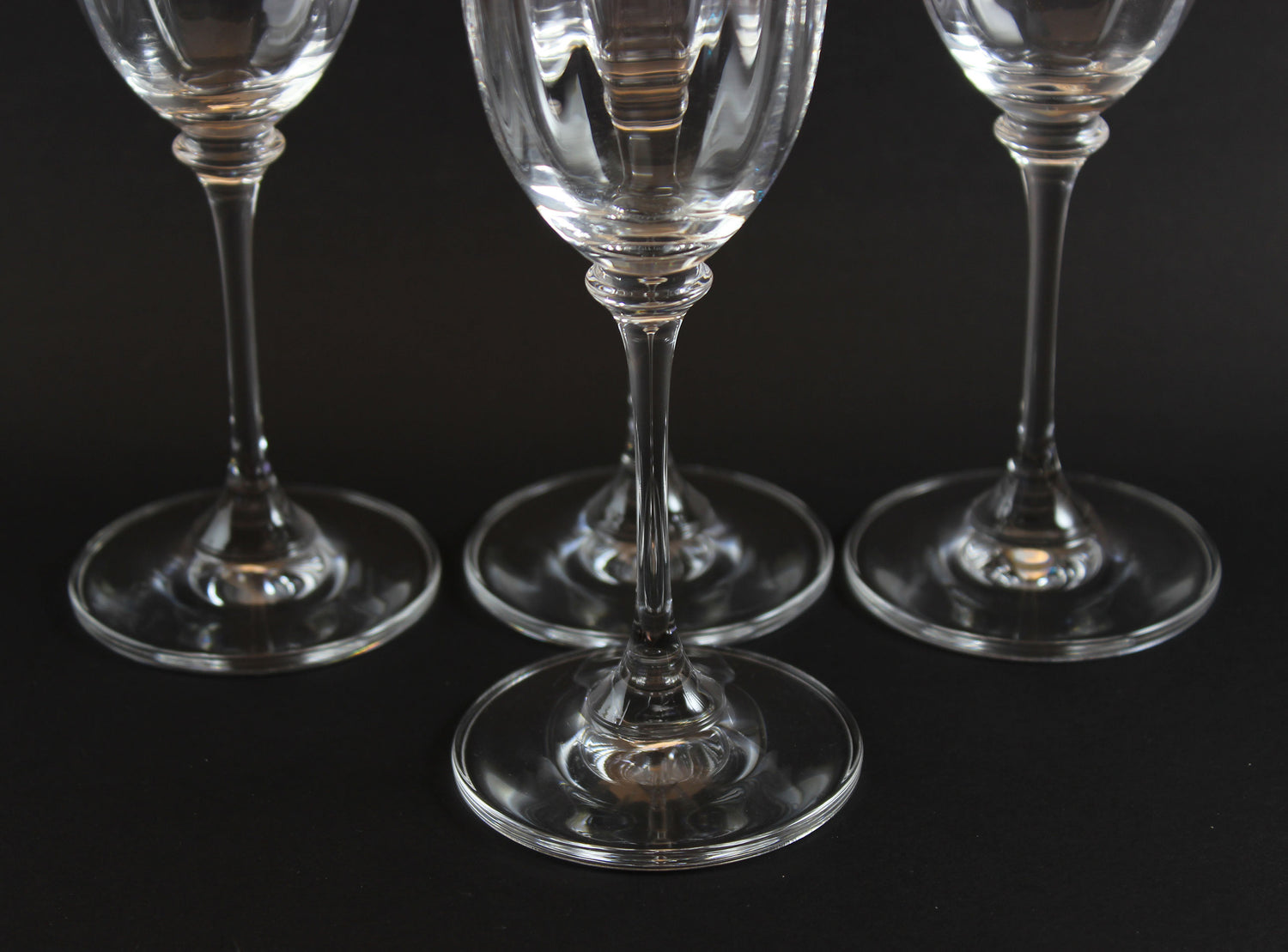 Four Mikasa Stephanie Pattern clear champagne flutes on a black background