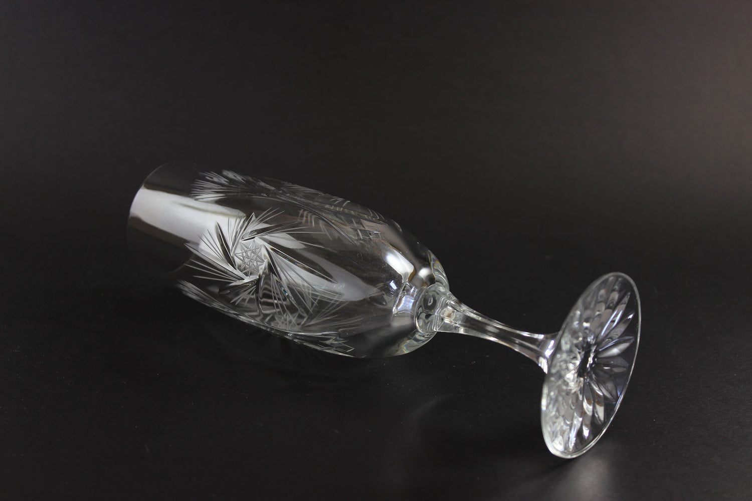 Two crystal champagne flutes with cut pinwheel design on a black background