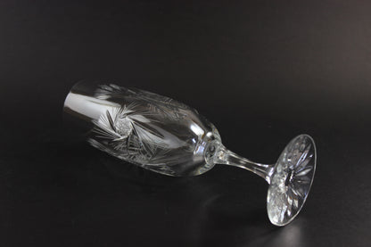Two crystal champagne flutes with cut pinwheel design on a black background