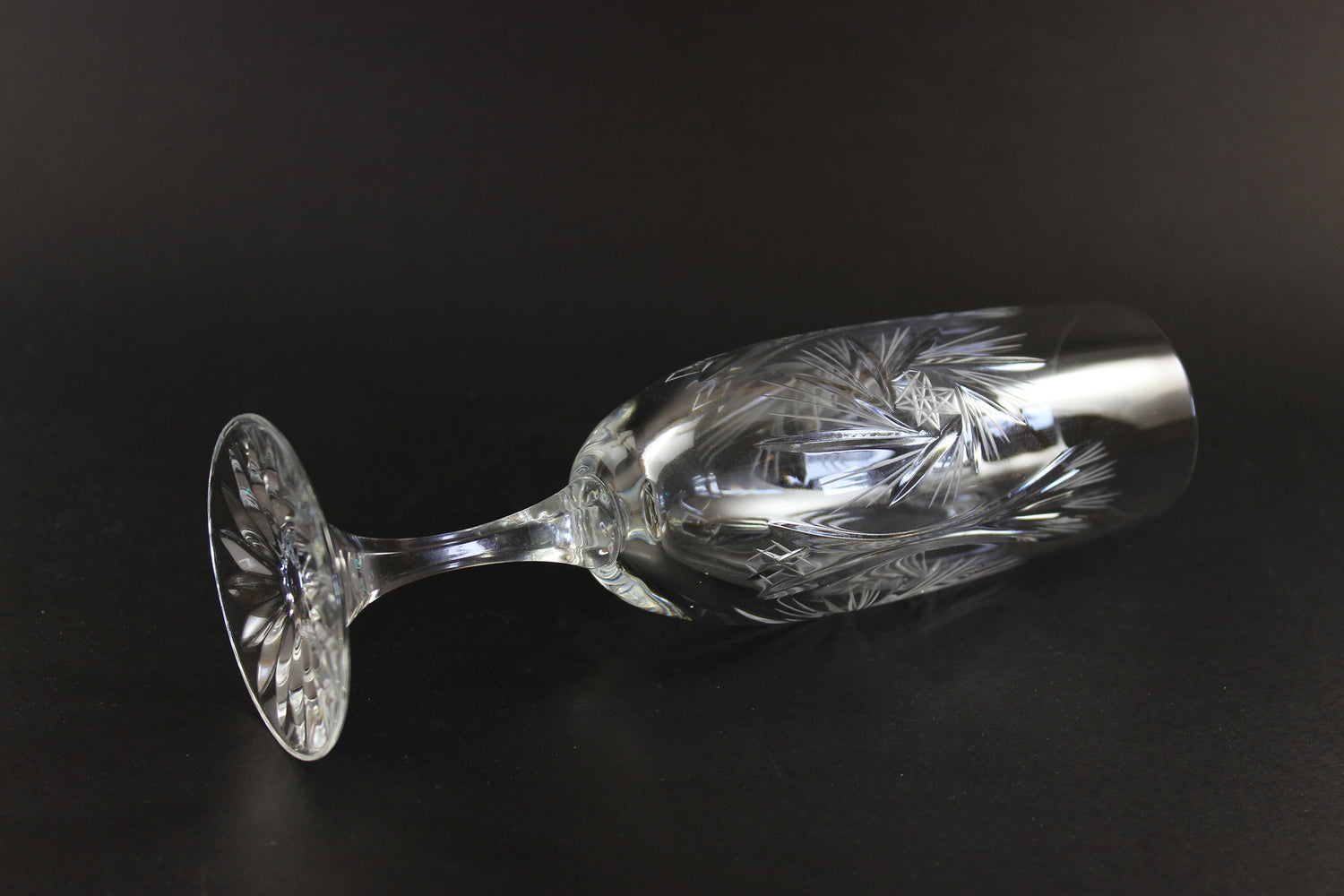 Two crystal champagne flutes with cut pinwheel design on a black background