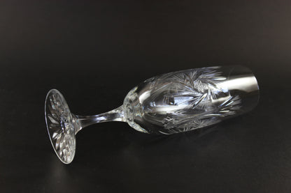 Two crystal champagne flutes with cut pinwheel design on a black background