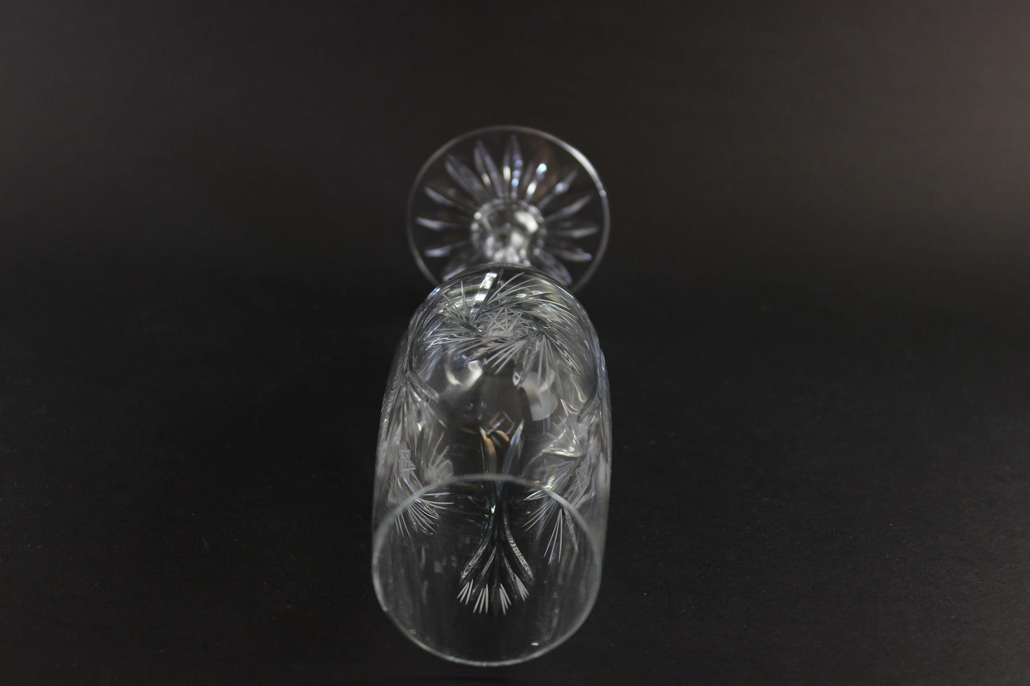 Two crystal champagne flutes with cut pinwheel design on a black background