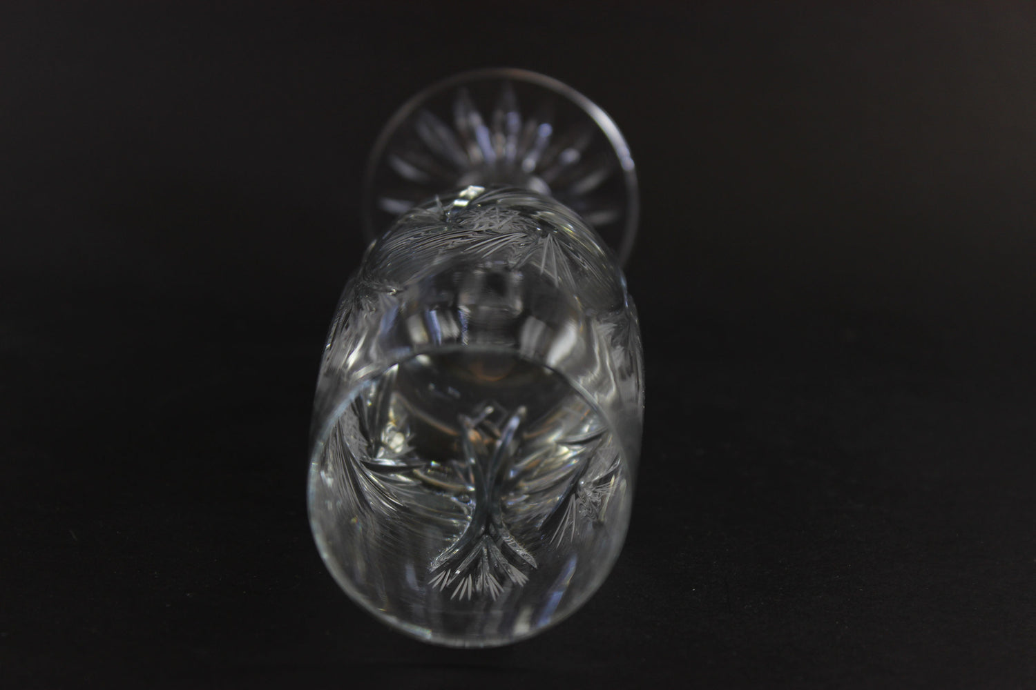 Two crystal champagne flutes with cut pinwheel design on a black background
