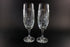 Two crystal champagne flutes with cut pinwheel design on a black background