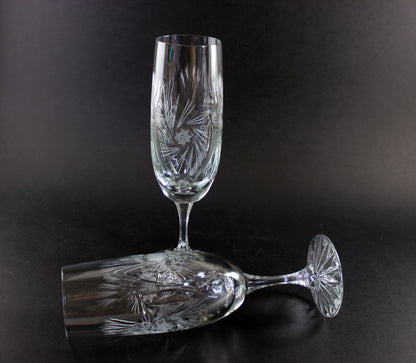 Two crystal champagne flutes with cut pinwheel design on a black background