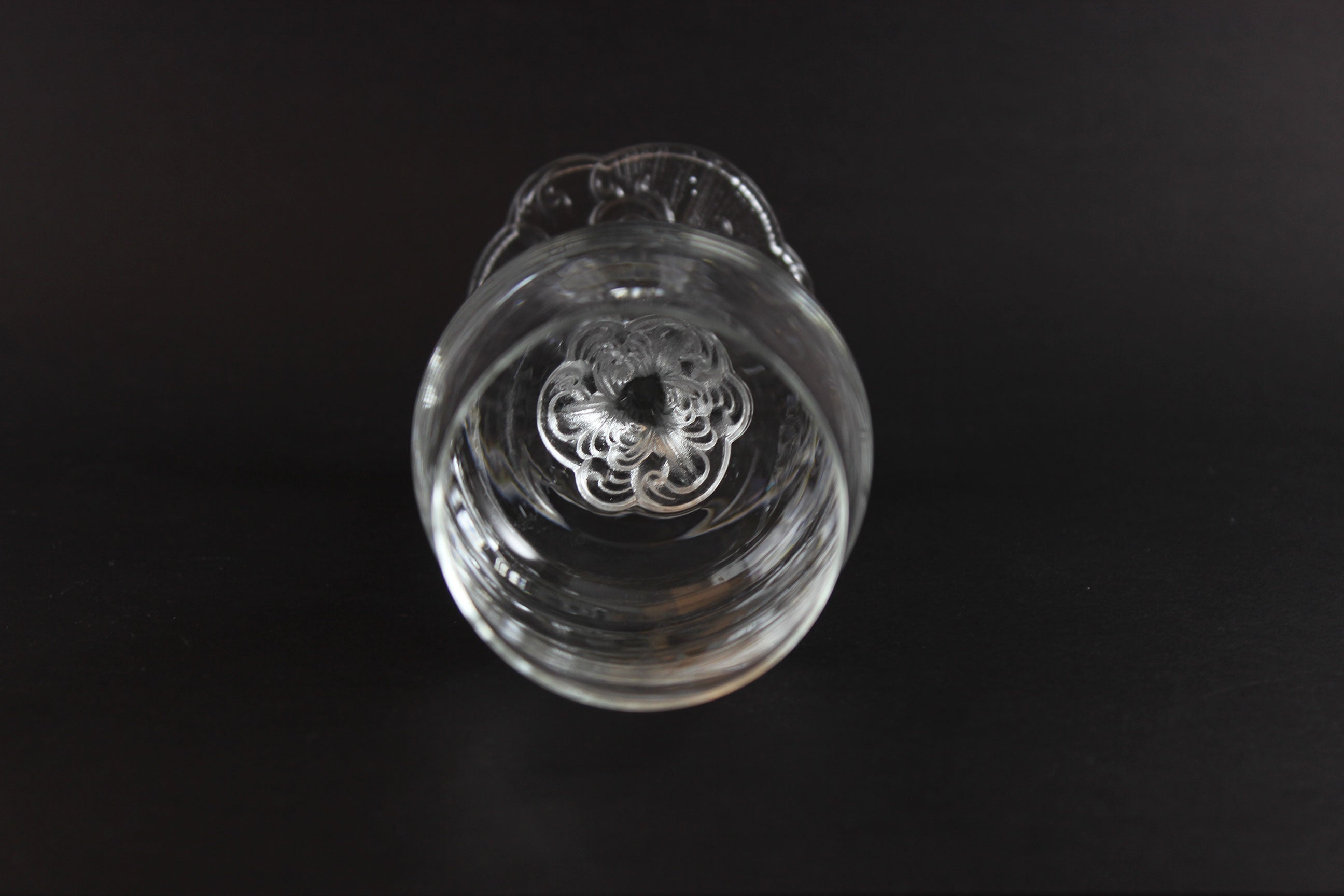 Clear glass object with intricate design on a black background