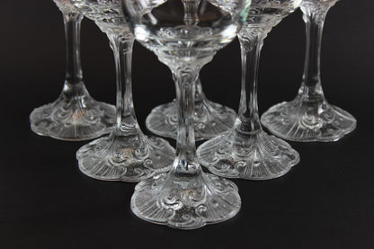 Set of clear glass cocktail glasses with intricate designs on a black background