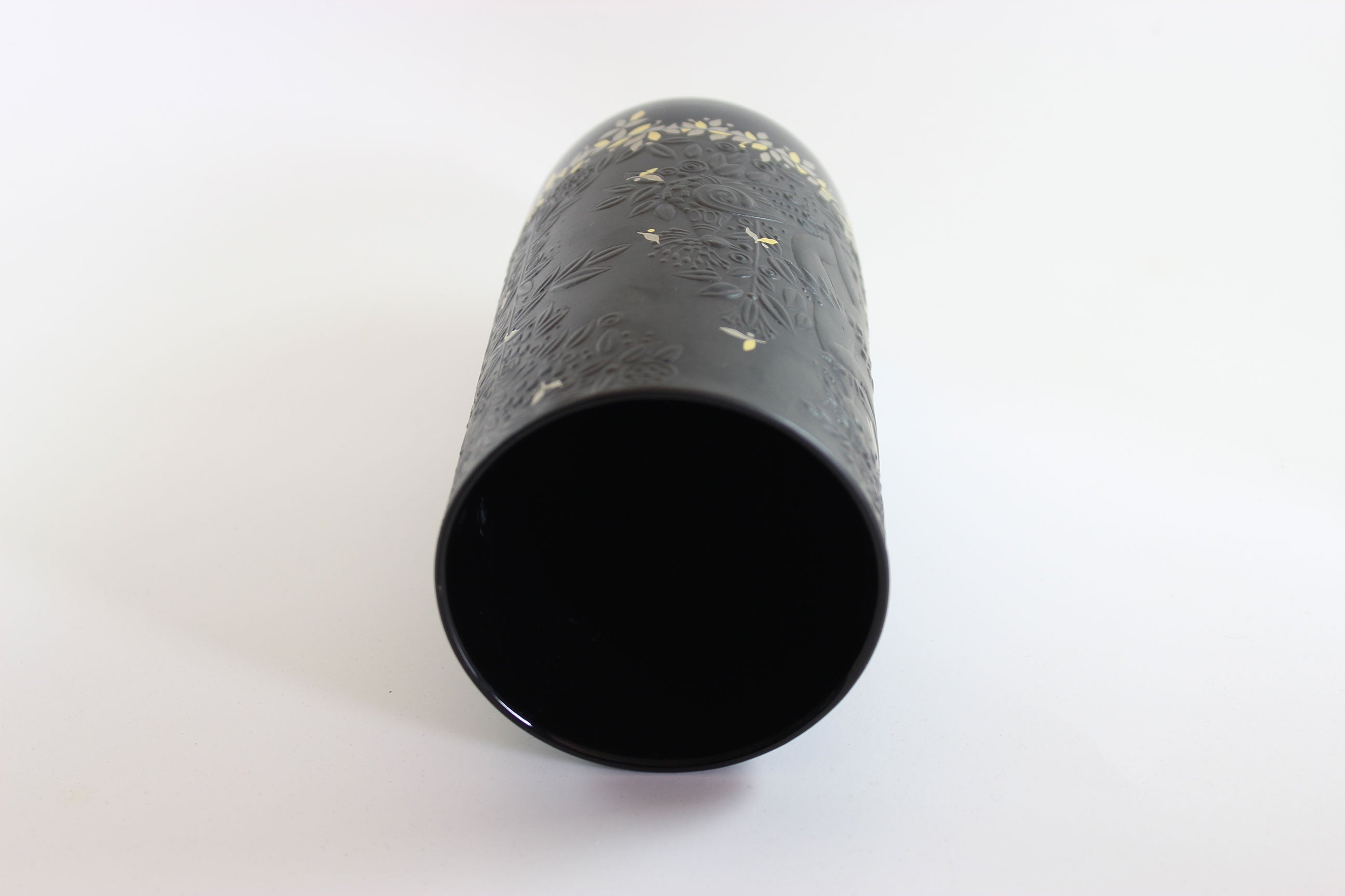 Black cylindrical object with textured surface on a white background