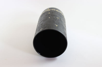 Black cylindrical object with textured surface on a white background