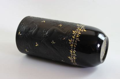 Black cylindrical object with gold floral patterns on a white background