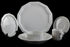 Six piece white porcelain dinnerware including plates, bowls, cup and saucer on a black background