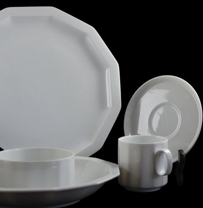 Six piece white porcelain dinnerware including plates, bowls, cup and saucer on a black background