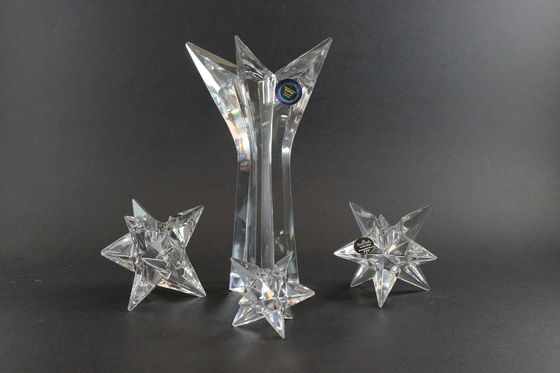 Set of crystal star-shaped candleholders on a dark background