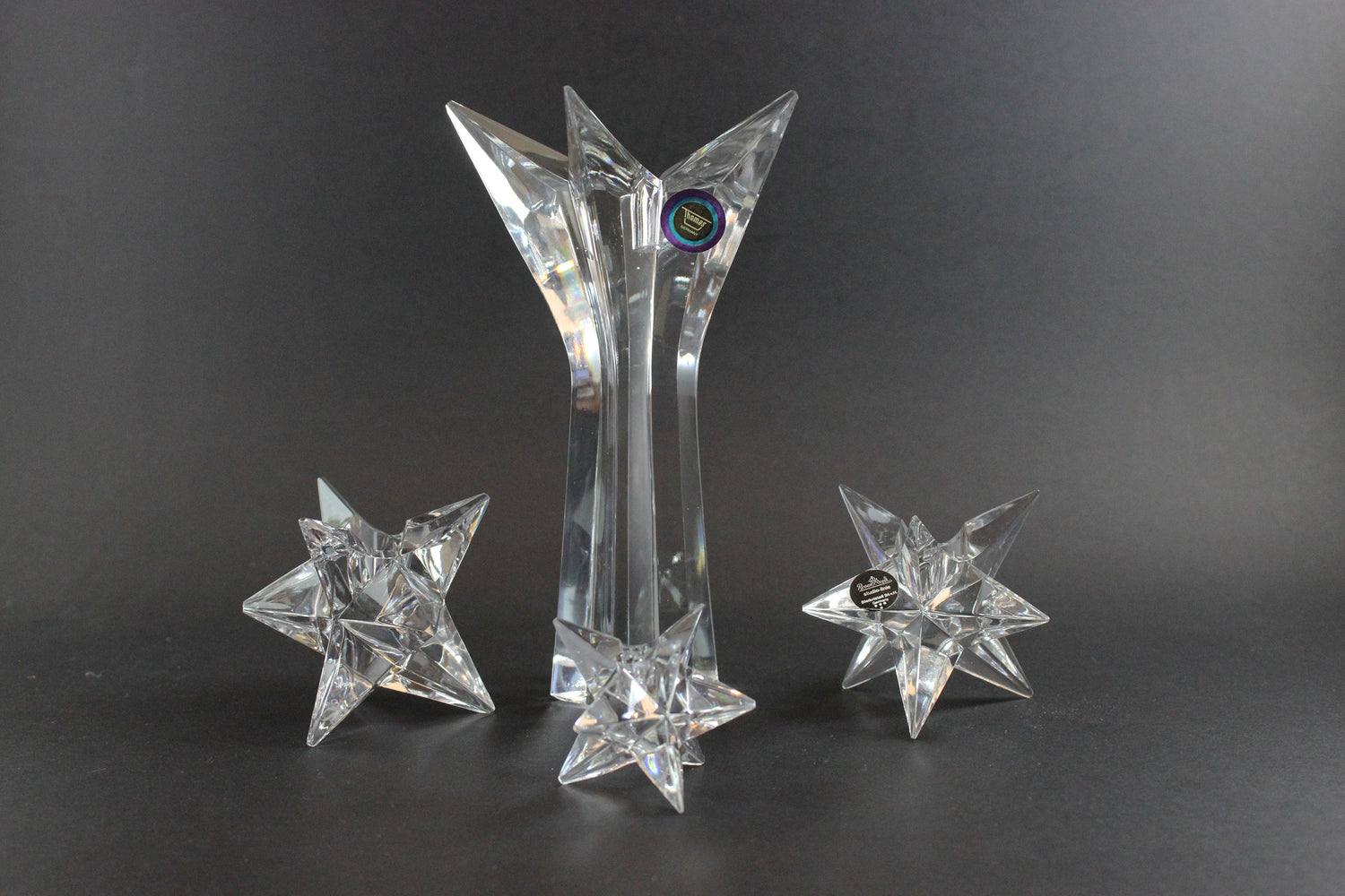 Set of crystal star-shaped candleholders on a dark background