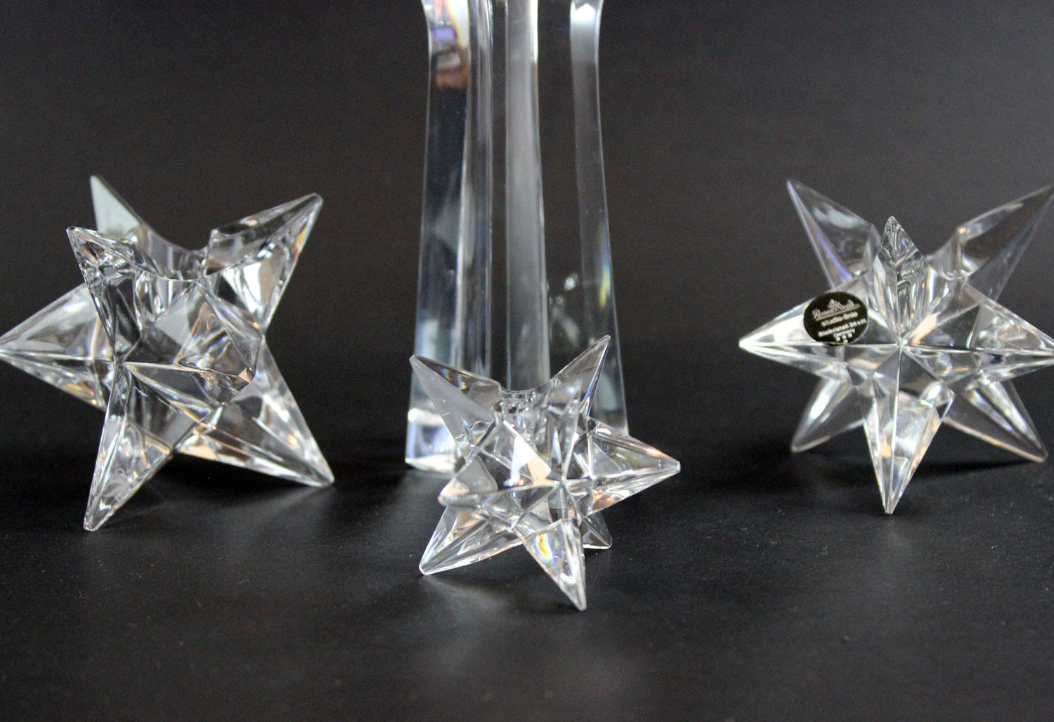 Set of crystal star-shaped candleholders on a dark background